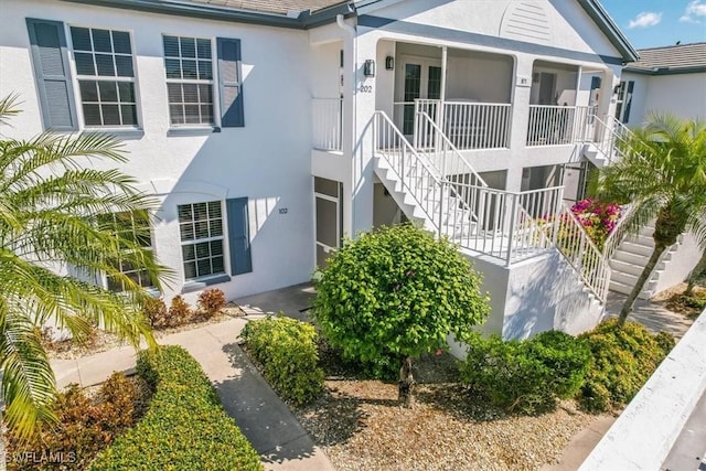 871 Tanbark Dr Unit 102, Naples, FL 34108 - view of side of property with stairway, stucco siding, and covered porch