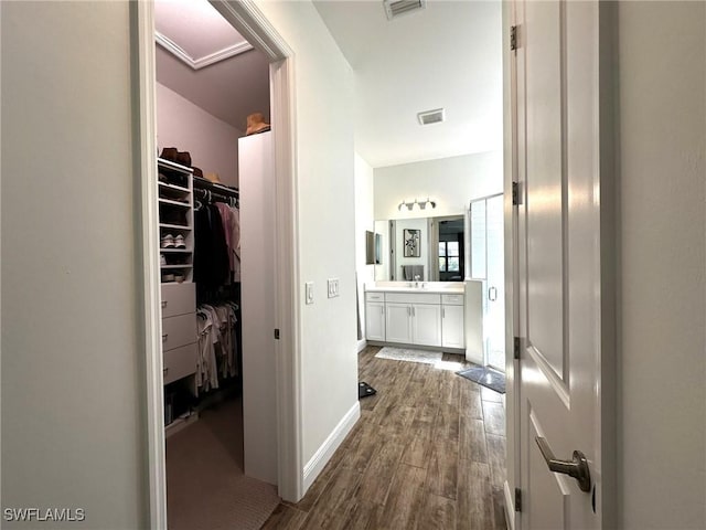 hall featuring a sink, dark wood finished floors, visible vents, and baseboards