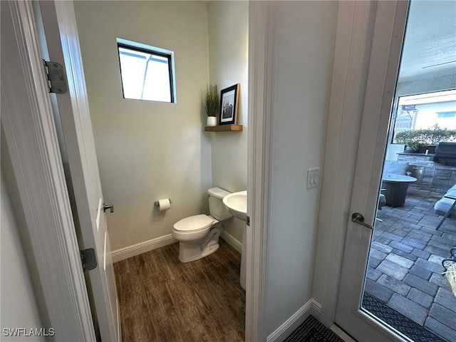 bathroom featuring baseboards, plenty of natural light, toilet, and wood finished floors