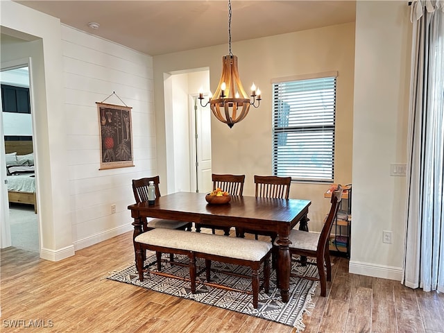 dining space with baseboards, light wood finished floors, and an inviting chandelier