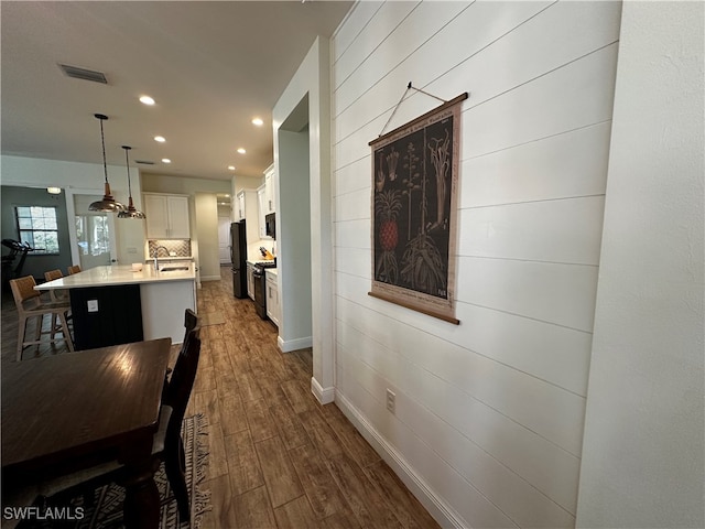 dining space with recessed lighting, wooden walls, dark wood-type flooring, visible vents, and baseboards