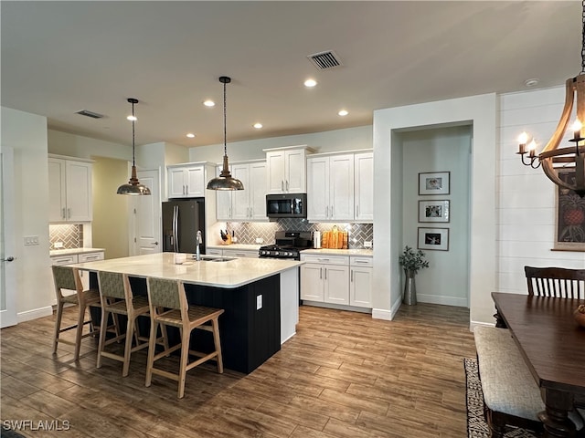 kitchen with black appliances, dark wood-style flooring, a sink, and visible vents