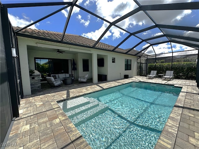 outdoor pool with glass enclosure, outdoor lounge area, a patio area, and a ceiling fan