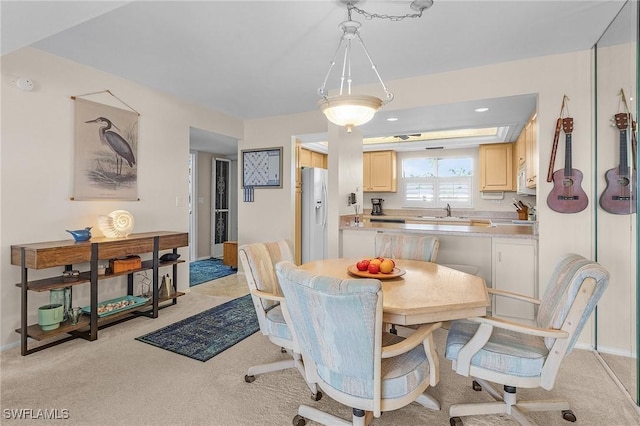 dining area with sink and light carpet