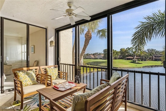 sunroom featuring ceiling fan, a healthy amount of sunlight, and a water view