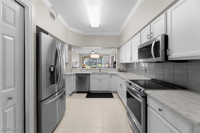 kitchen with white cabinetry, ornamental molding, appliances with stainless steel finishes, and light tile patterned flooring