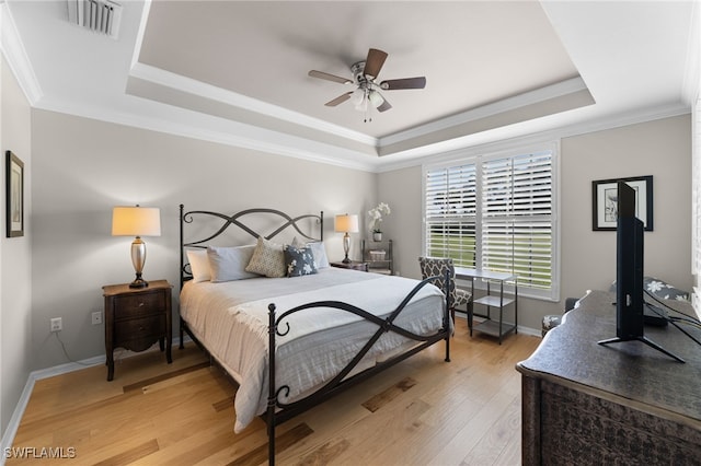 bedroom with wood-type flooring, ornamental molding, a raised ceiling, and ceiling fan