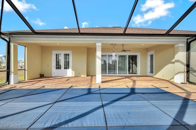 rear view of house featuring french doors, ceiling fan, glass enclosure, and a patio area