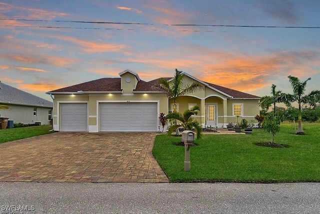 view of front of home with a garage and a lawn