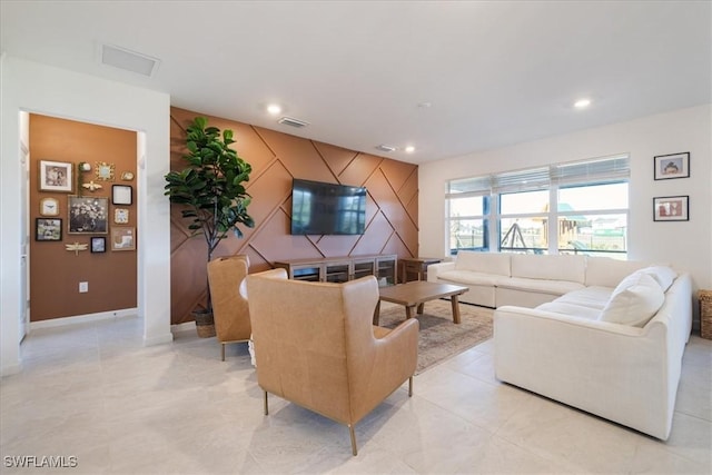 living area with recessed lighting, visible vents, baseboards, and an accent wall