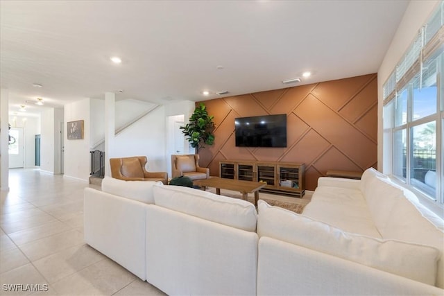 living room with an accent wall, light tile patterned flooring, recessed lighting, and stairs