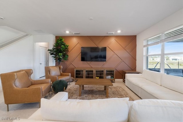 living area featuring visible vents, recessed lighting, and an accent wall