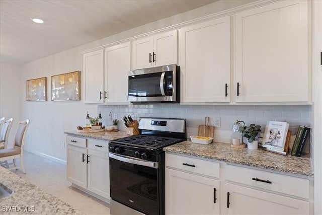 kitchen with white cabinetry, light stone counters, backsplash, and appliances with stainless steel finishes