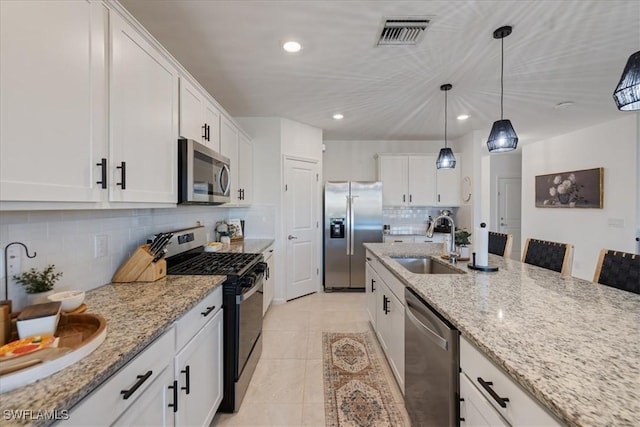 kitchen featuring visible vents, light tile patterned flooring, white cabinets, stainless steel appliances, and a sink