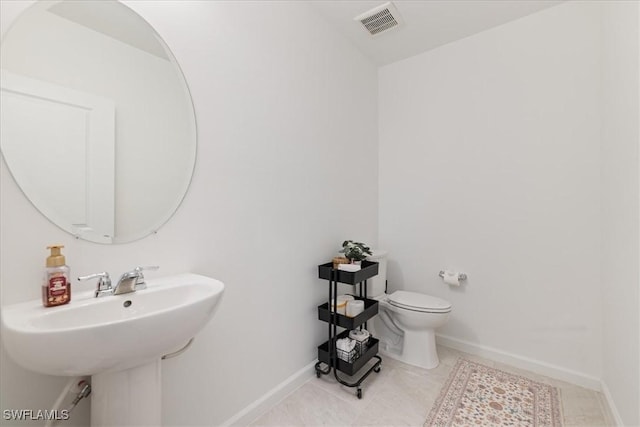 half bathroom featuring visible vents, baseboards, toilet, and tile patterned flooring