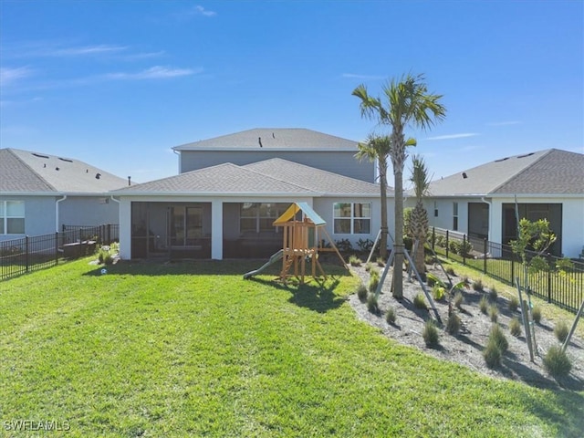 back of house featuring a playground, a sunroom, and a lawn