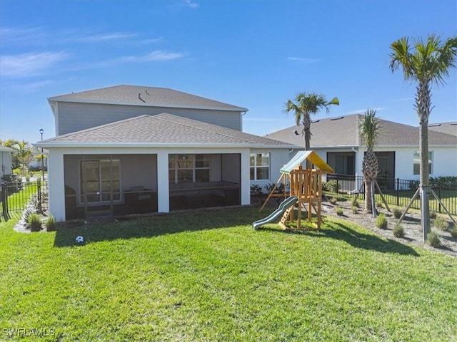 rear view of house featuring a lawn, a sunroom, and a playground