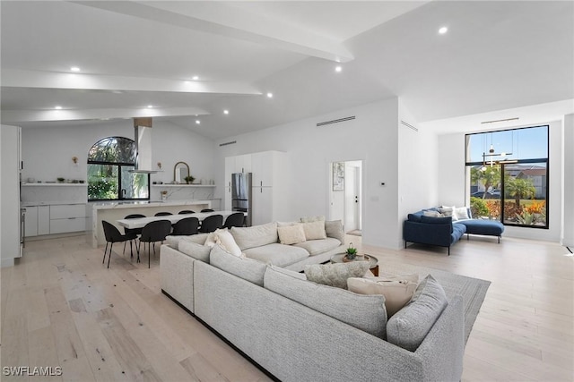 living room with high vaulted ceiling, beam ceiling, and light hardwood / wood-style flooring