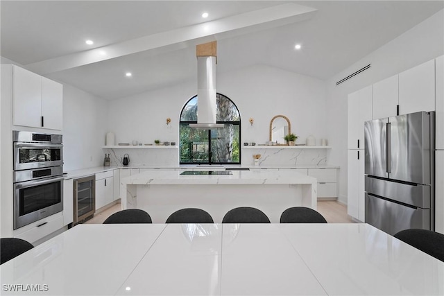 kitchen with a kitchen island, appliances with stainless steel finishes, beverage cooler, and a kitchen breakfast bar