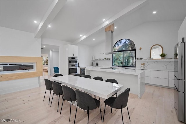 dining space featuring lofted ceiling with beams and light hardwood / wood-style floors