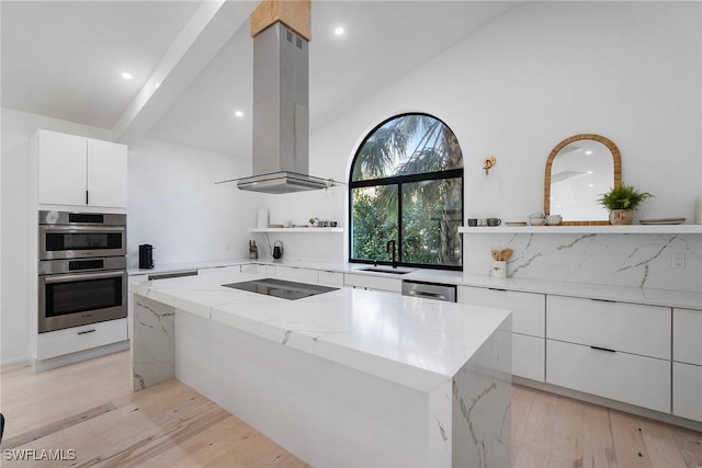 kitchen featuring island range hood, a center island, light hardwood / wood-style flooring, stainless steel appliances, and light stone countertops