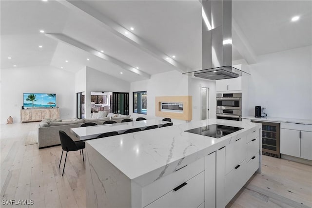 kitchen featuring a large island, white cabinetry, double oven, wine cooler, and light stone countertops