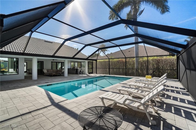 view of swimming pool featuring ceiling fan, an outdoor hangout area, glass enclosure, and a patio area