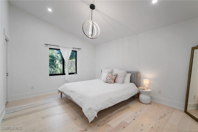 bedroom featuring an inviting chandelier, lofted ceiling, and light hardwood / wood-style floors