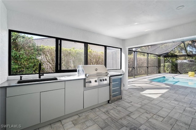 view of patio featuring area for grilling, beverage cooler, sink, and glass enclosure