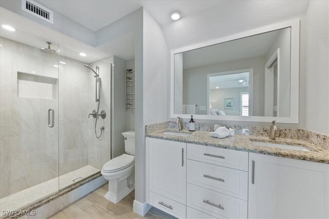 bathroom featuring vanity, toilet, and a shower with door