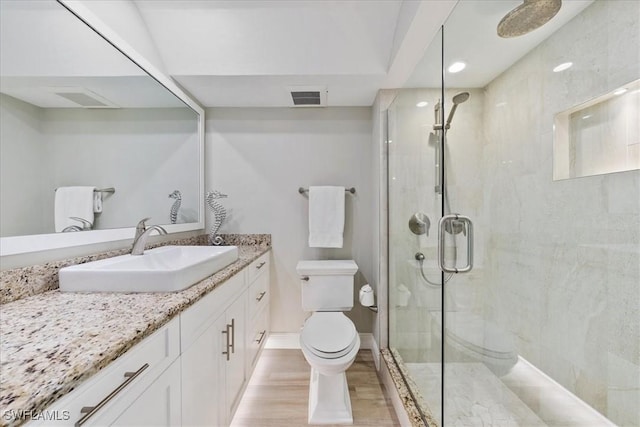 bathroom featuring vanity, an enclosed shower, wood-type flooring, and toilet