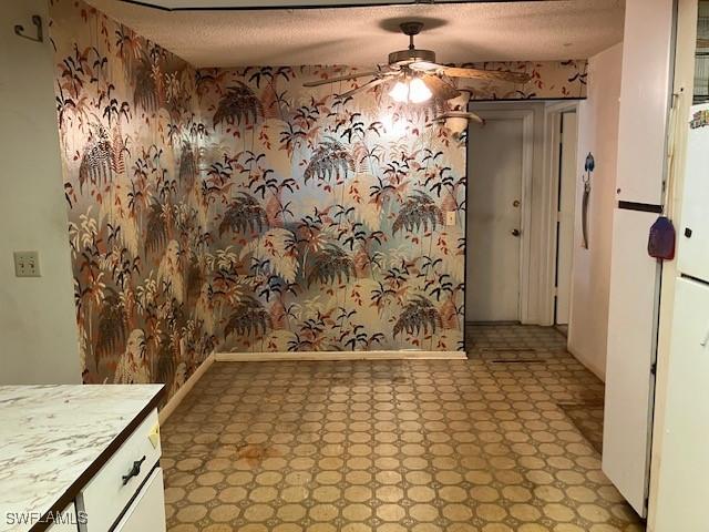 unfurnished dining area with ceiling fan and a textured ceiling