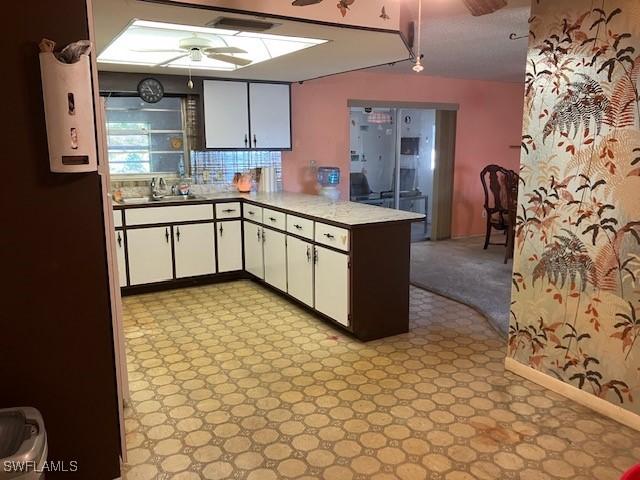 kitchen with white cabinetry, sink, ceiling fan, and kitchen peninsula