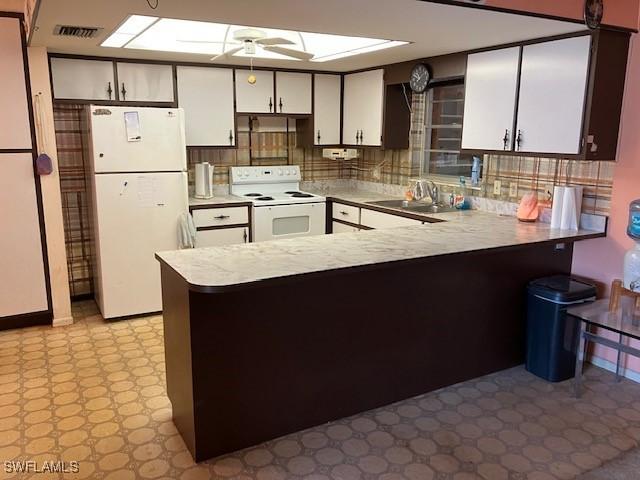 kitchen featuring sink, white appliances, a skylight, kitchen peninsula, and ceiling fan