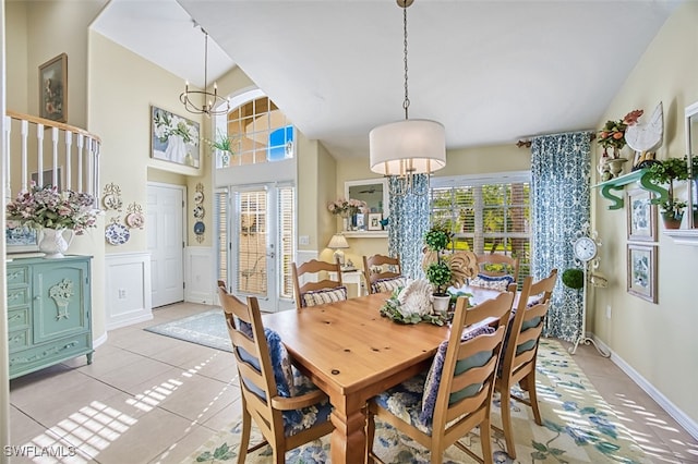 dining room featuring light tile patterned floors, a notable chandelier, french doors, and a high ceiling