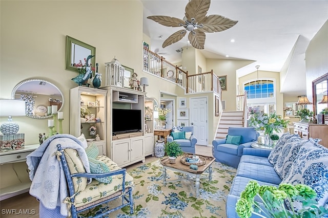 living room with ceiling fan and a towering ceiling