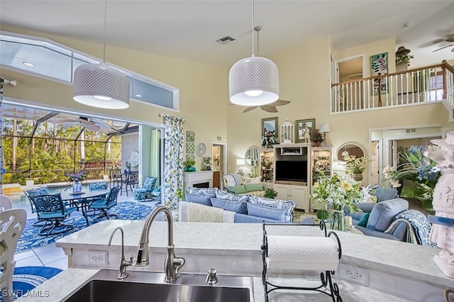 kitchen with sink, a towering ceiling, light tile patterned floors, and ceiling fan