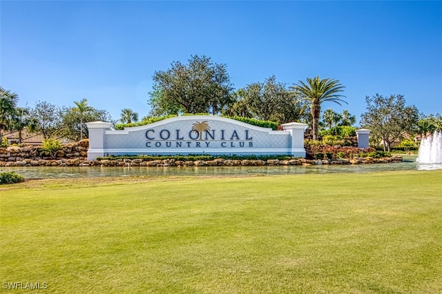 community / neighborhood sign with a lawn and a water view