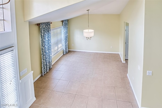 unfurnished dining area with baseboards, visible vents, light tile patterned floors, and lofted ceiling