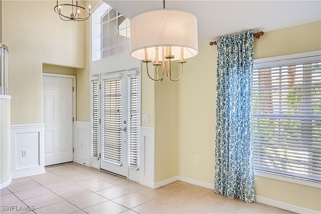 unfurnished dining area featuring a notable chandelier, tile patterned flooring, and a wainscoted wall
