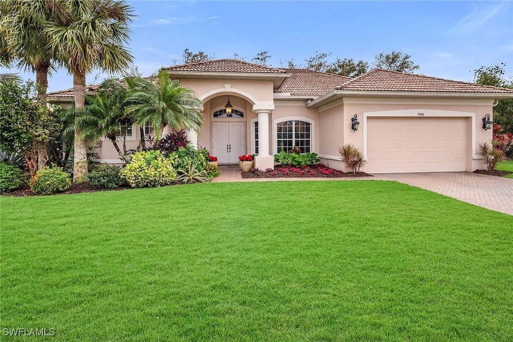 mediterranean / spanish home featuring a garage and a front lawn