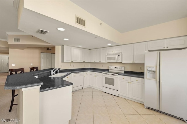 kitchen with a breakfast bar area, white cabinets, white appliances, and kitchen peninsula