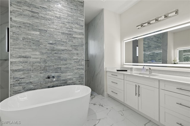 bathroom with vanity, a washtub, and tile walls