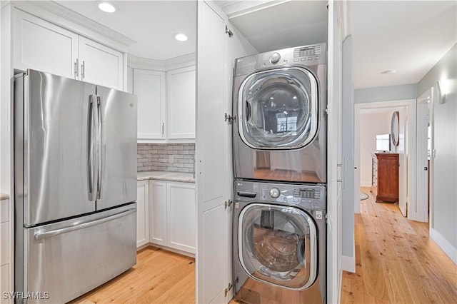 laundry area with stacked washer / dryer and light wood-type flooring