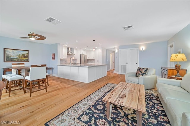 living room with ceiling fan, sink, and light wood-type flooring