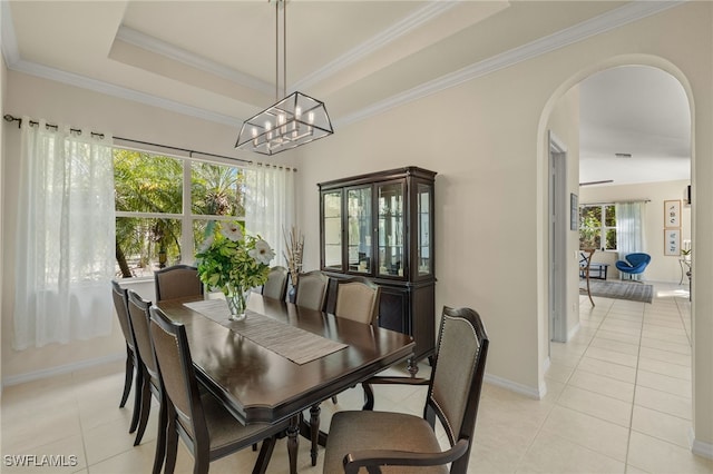 tiled dining area with a raised ceiling, crown molding, and an inviting chandelier