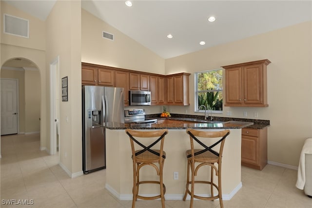 kitchen featuring appliances with stainless steel finishes, a center island, sink, and dark stone countertops