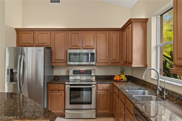 kitchen with appliances with stainless steel finishes, sink, and dark stone countertops