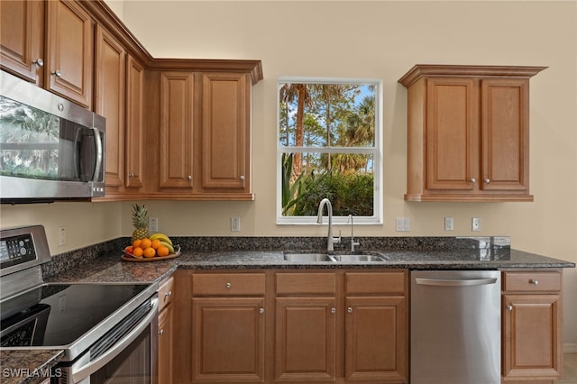 kitchen with stainless steel appliances, sink, and dark stone countertops