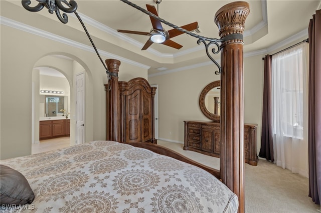 carpeted bedroom featuring crown molding, a tray ceiling, and ensuite bathroom